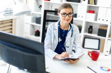 Beyaz bir elbise içinde genç bir kız ofiste bir masada oturur ve bir kalem ve defter elinde tutar. Bir stetoskop boynunda asılı.