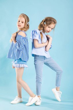 Mavi bir arka plan üzerinde kız ikiz ışık mavi giysiler içinde poz.