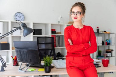 Genç bir kız ofiste bir masaya yaslanmış duruyor..