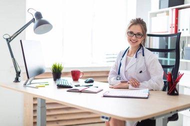 Beyaz bir elbise içinde genç bir kız bilgisayar masasında oturuyor.