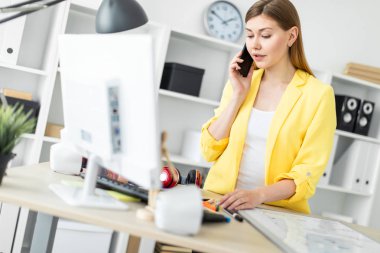 Genç bir kız bir masanın ayakta, telefonda konuşurken ve bir bilgisayarla çalışma. Önce kız masanın üzerinde bir manyetik tahta