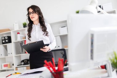 Güzel bir genç kız bir ofis masası standları ve notlar için bir sayfası tutar.