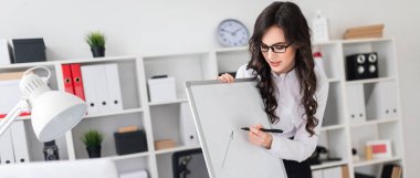 Güzel bir genç kız bir Ofis Masası standları ve manyetik bir işaretleyici manyetik tahtaya çizer.