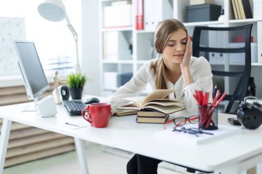 Genç bir kız elini yanağı ofis ve propps bir masada oturur.