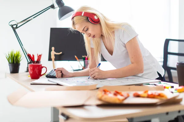 Uma jovem nos fones de ouvido fica perto da mesa e tem um marcador na mão. Na mesa está uma placa magnética . — Fotografia de Stock