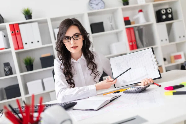 Een mooi jong meisje is zittend aan een tafel in het kantoor en een potlood wijzend op de informatie in het document. — Stockfoto