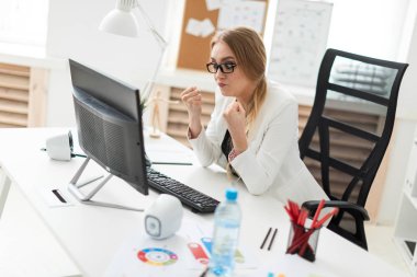Ofiste masada oturan, iki yumruk gösterilen ve ekrana bakarak Genç kız.