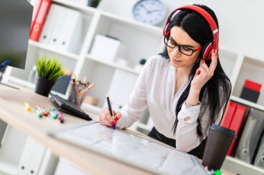 Genç bir kız kulaklık tablo anlamına gelir ve bir işaretleyici manyetik bir tahtaya çizer.