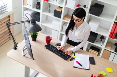 Genç bir kız masanın ayakta ve metin klavyede yazarak. Belgeler ve bir işaretleyici kızın yanında yalan.