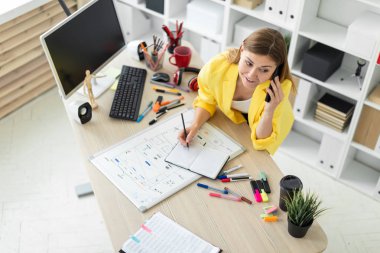 Genç bir kız bir masanın ayakta, telefonda konuşurken, onun elinde bir kalem tutan ve notları bir defterde yapma. Önce kız masanın üzerinde bir manyetik tahta