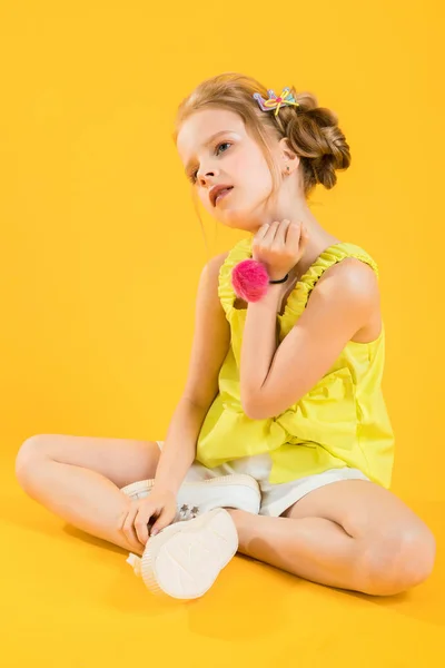 Una adolescente está sentada sobre un fondo amarillo . — Foto de Stock