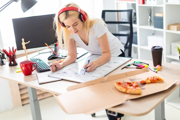 A young girl in the headphones stands near the table and holds a marker in her hand. On the table is a magnetic board. — Stock Photo, Image
