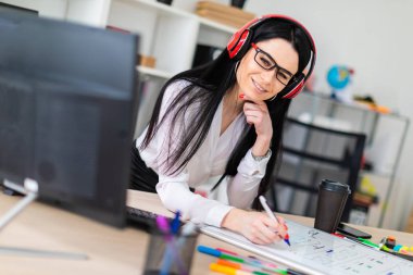 Genç bir kız kulaklık tablo anlamına gelir ve bir işaretleyici manyetik bir tahtaya çizer.