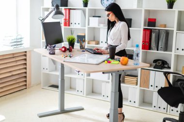 Genç bir kız bir tablo duruyor ve klavyede yazdırır. Kız bir manyetik kurulu ve işaretleri olmadan.