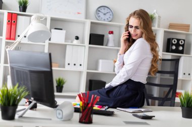 Güzel bir genç kız ofiste masaya oturdu ve telefonda konuşuyordum. Hoşlandığın kızın önünde belgeleri vardır.