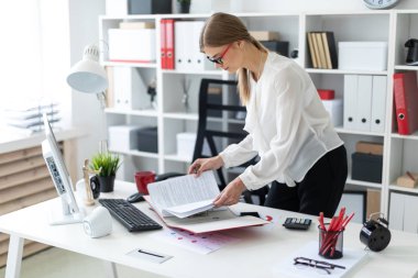 Genç bir kız tablo bükülmüş duruyor, onun elinde bir kalem tutan ve belgeler klasörüyle aracılığıyla döndürür.