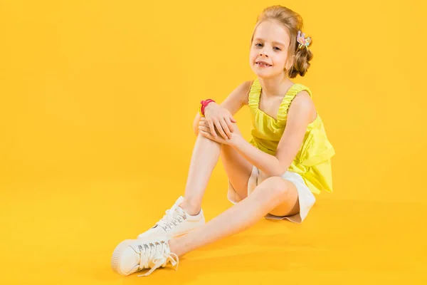 Una adolescente está sentada sobre un fondo amarillo . — Foto de Stock