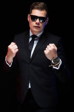 Onun güç ve güven boks siyah arka plan üzerinde gösterilen güneş gözlüğü emin yakışıklı zarif işadamı portresi