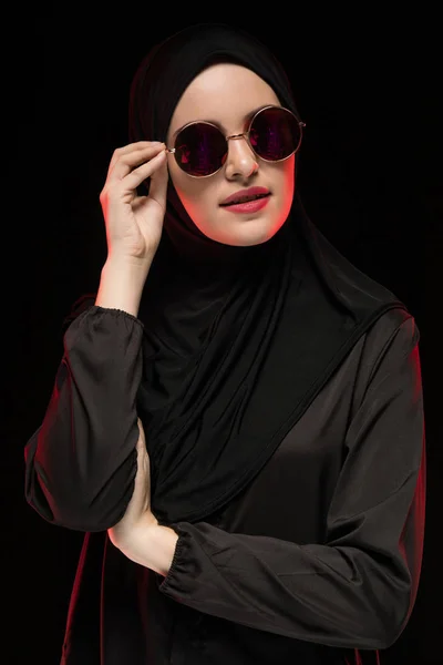 黒い背景にポーズの東の現代のファッション概念として黒のヒジャーブとサングラスを着て美しいスタイリッシュな若いイスラム教徒の女性の肖像画 — ストック写真