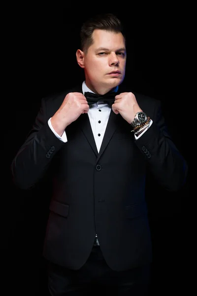 Porträt eines selbstbewussten gutaussehenden eleganten Geschäftsmannes mit Fliege auf schwarzem Hintergrund im Studio — Stockfoto