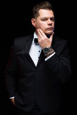 Emin yakışıklı şık şık işadamı papyon holding elle sakal Studio siyah arka plan üzerine yakınındaki portresi