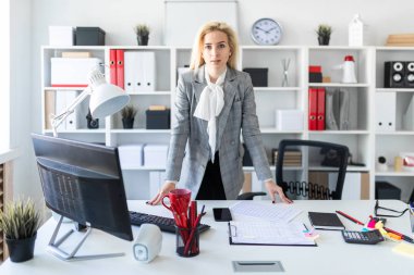 Genç bir kız ofiste standları, ellerini masanın koy.