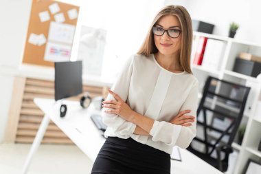 Genç bir kız ofiste bir masaya yaslanmış duruyor..