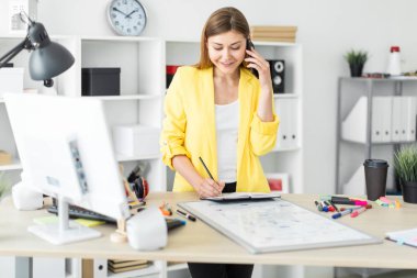 Genç bir kız bir masanın ayakta, telefonda konuşurken, onun elinde bir kalem tutan ve notları bir defterde yapma. Önce kız masanın üzerinde bir manyetik tahta