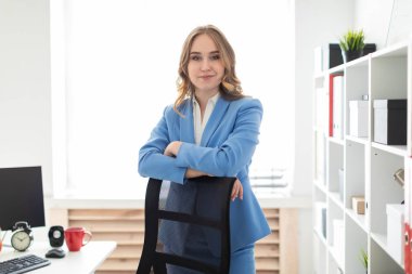 Güzel bir genç kız bir raf ofiste, yakın onu dirsek bir sandalyenin arkasına koyarak standları.