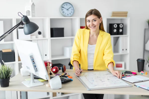 En ung flicka står nära en tabell, innehar en markör i handen och arbetar med en magnetisk anslagstavla. — Stockfoto