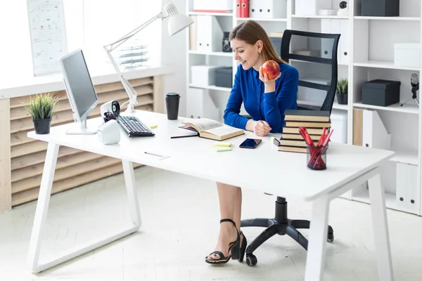 Genç bir kız bir bilgisayar masada oturur ve bir elma elinde tutar. Önce kız açık bir kitap yatıyor.