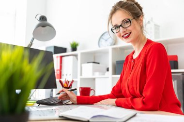 Genç bir kız ofiste bir masada duruyor ve bir siyah kalemi elinde tutan.