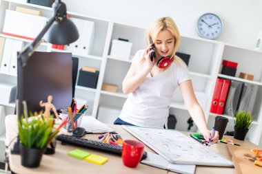 Genç bir kız bir masanın ayakta, telefonda konuşurken ve bir işaretleyici elinde tutan. Masaya manyetik bir pansiyondur. Kızlar kulaklık boynuna asmak.