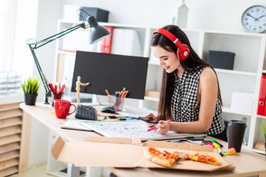 Genç bir kız bir tablo duruyor ve bir işaretleyici ve telefon elinde tutar. Bir manyetik tahta tablodur.