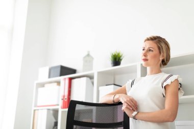 Genç sarışın kız yanındaki belgelerle, raf ofiste ellerini Koltuğun arkasında bekleyen.