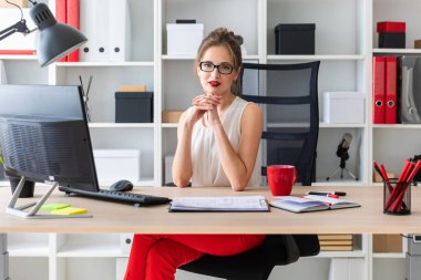 Genç bir kız ofiste masada oturuyor.