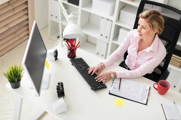 Een jong meisje is zittend aan een tafel in het kantoor en te typen op het toetsenbord. — Stockfoto