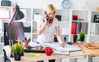 Genç bir kız bir masanın ayakta, telefonda konuşurken ve bir işaretleyici elinde tutan. Masaya manyetik bir pansiyondur. Kızlar kulaklık boynuna asmak.