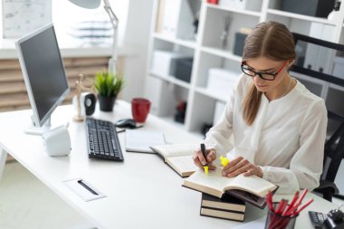 Genç bir kız ofiste bir masada oturur ve sarı bir işaret onun elinde tutar. Önce kız açık bir kitap yatıyor.