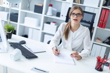 Genç bir kız ofiste bir masada oturur ve onun elinde kalem tutan. Önce kız açık bir kitap yatıyor.