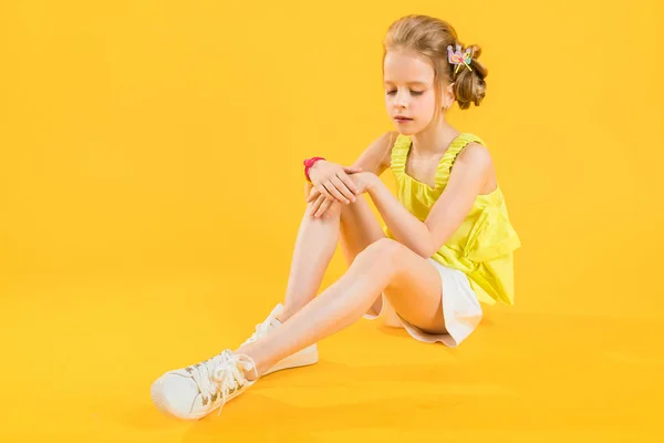Una adolescente está sentada sobre un fondo amarillo . — Foto de Stock