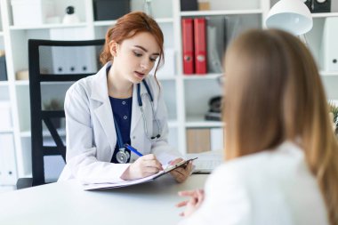 Beyaz bir elbise içinde güzel bir genç kız ofiste masada oturan ve muhatap ile iletişim. Kız notlar sayfasında yapar..