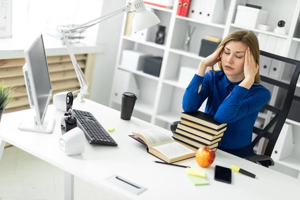 Ein junges Mädchen sitzt an einem Computertisch und hält sich die Hände hinter den Kopf. vor dem Mädchen liegt ein offenes Buch. — Stockfoto