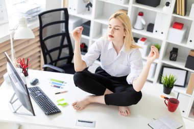 oturma ve ofiste bir tablo üzerinde meditasyon genç iş kadını.