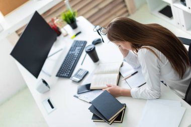 Tablo ve bir bilgisayar, belge ve hesap makinesi ile çalışır bir genç kız oturdu