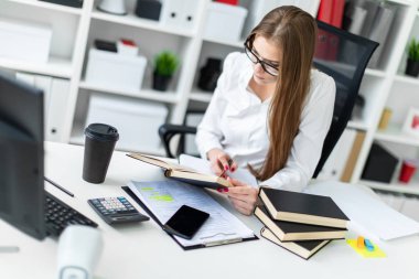Tablo ve bir bilgisayar, belge ve hesap makinesi ile çalışır bir genç kız oturdu