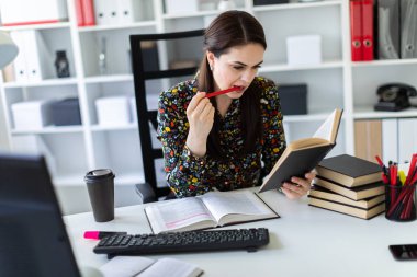 economist with pen in hand attentively reading business book and sitting at table in bright office 