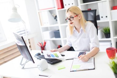 bir bilgisayar ve belgeler ile ofiste çalışan genç iş kadını.