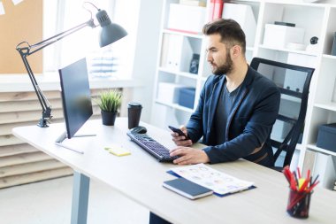 Zeki bir genç adam parlak bir ofisi telefon ile çalışır. 