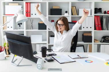 Genç kız ofiste bir bilgisayar masasında oturan ve ellerini kaldırdı